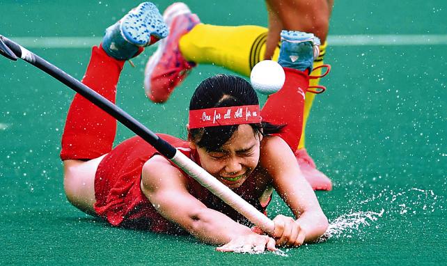 「全力 輝く夏」ホッケー女子準決勝、激しい競り合いで転倒する石動(富山)の佐野里名。摩擦によるけがを防ぐためまかれた水が飛び散る(7月31日、岐阜県各務原市で) ©読売新聞社