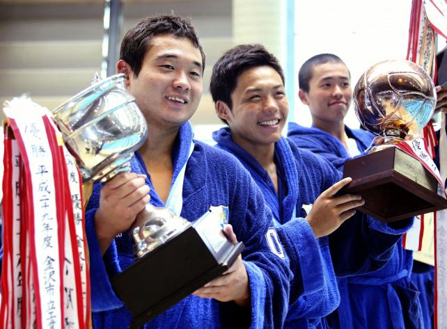 水球で3連覇を達成し、優勝杯を手に笑顔の金沢市工の(左から)宮沢拓夢、原宏斗ら ©読売新聞社