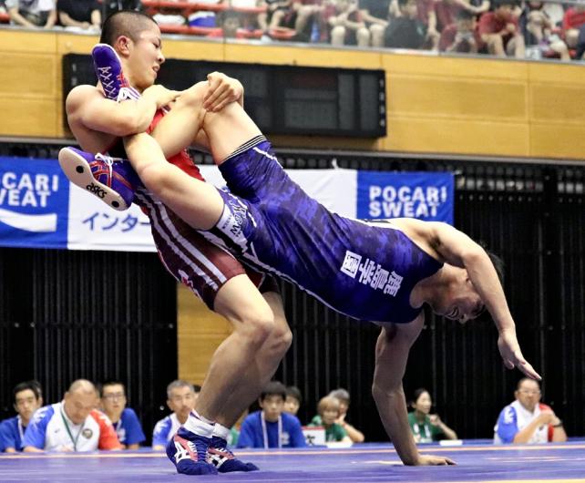 脚を固めて相手を持ち上げる秋田商の山下選手(左)