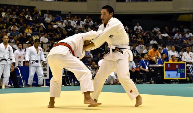 柔道男子73キロ級の1回戦で攻める鹿児島情報の岩坪選手(右)