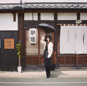 日焼け対策バッチリ！古風なお店の前に立つ美人は誰!?